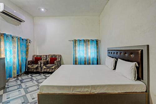 1 dormitorio con 1 cama grande y 1 silla en OYO Riddhi Siddhi Hotel And Marriage Garden 