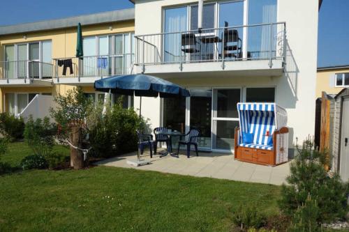 ein Haus mit einer Terrasse mit einem Tisch und einem Sonnenschirm in der Unterkunft Küstenwald - Ferienwohnung Igelring H in Müritz