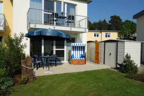 ein Haus mit einer Terrasse mit einem Tisch und Stühlen in der Unterkunft Küstenwald - Ferienwohnung Igelring H in Müritz