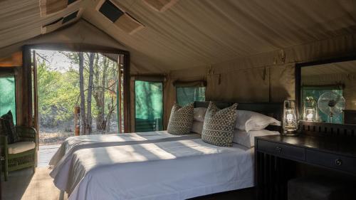 una camera con un grande letto in una tenda di Mashatu Tent Camp a Lentswelemoriti