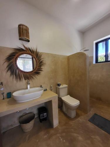 a bathroom with a sink and a toilet and a mirror at Sand Beach Boutique Villas in Bwejuu