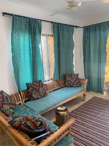 a couch in a living room with green curtains at Sand Beach Boutique Villas in Bwejuu