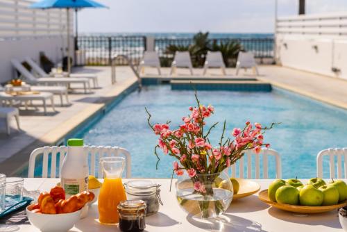 a table with fruit and a vase of flowers next to a pool at Faros Seaside Villa Larnaca in Perivolia