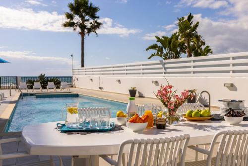 a white table with fruit on it next to a swimming pool at Faros Seaside Villa Larnaca in Perivolia