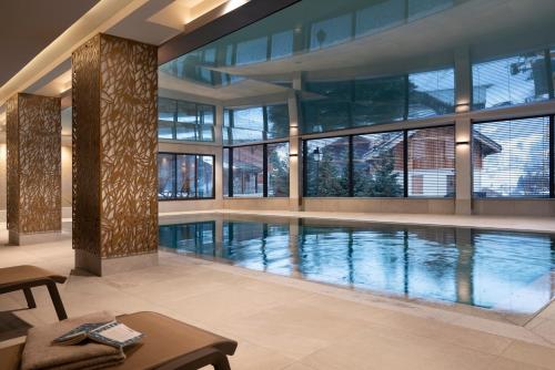 a large swimming pool in a building with windows at Les Chalets Laska in Les Contamines-Montjoie