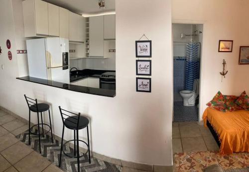 - une cuisine avec un comptoir et deux tabourets dans une pièce dans l'établissement Apê frente para o mar - pé na areia, à São Vicente
