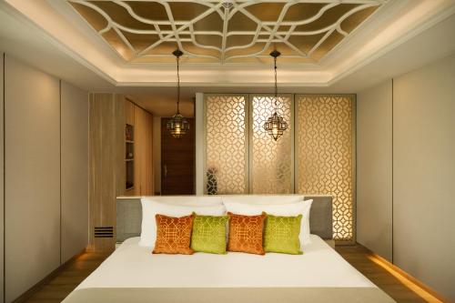 a bedroom with a white bed with colorful pillows at Avista Grande Phuket Karon - MGallery in Karon Beach