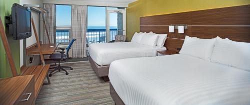 a hotel room with two beds and a desk and a television at Holiday Inn Express Nags Head Oceanfront by IHG in Nags Head