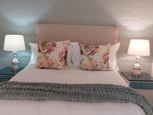 a bedroom with a bed with pillows and two lamps at Hide Away on 21 in Mossel Bay