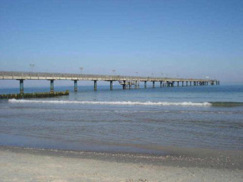 a pier in the ocean with waves and a beach at Villa Quisisana in der Kurstraße EG in Graal