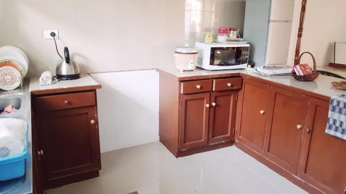 eine Küche mit Holzschränken und einer Mikrowelle in der Unterkunft Jetpoint Furnished 2 bedroom in Nadi