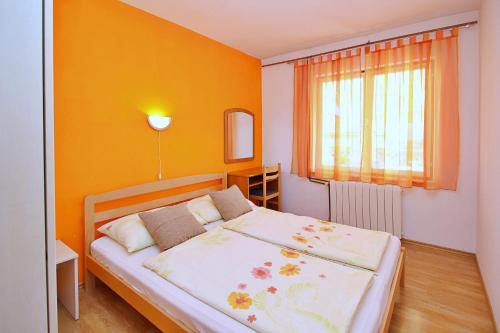 1 dormitorio con 1 cama con pared de color naranja en Apartments Andelka G, en Šilo