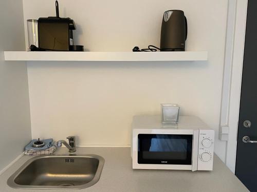 a microwave sitting on a counter next to a sink at KragenæsHus in Torrig