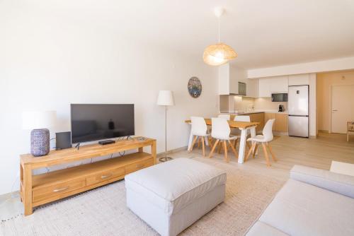 a living room with a television and a table at Moon Beach House in Praia da Areia Branca