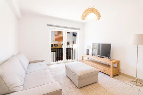 a white living room with a couch and a tv at Moon Beach House in Praia da Areia Branca
