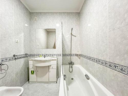La salle de bains blanche est pourvue d'une baignoire et d'un lavabo. dans l'établissement Comfortable apartment in Viana do Castelo, à Viana do Castelo