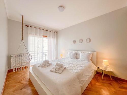 - une chambre avec un lit doté de draps blancs et une fenêtre dans l'établissement Comfortable apartment in Viana do Castelo, à Viana do Castelo