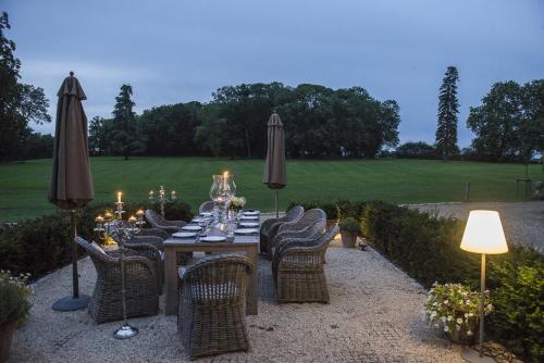 a table with chairs and umbrellas in a garden at Château de Planchevienne in Magny-Cours