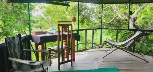 Habitación con porche con mesa y sillas. en Jungle Cabin, en Bundala Levagamgoda