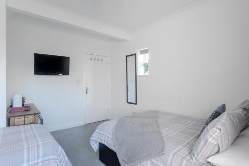 a white bedroom with a bed and a tv on the wall at Apple House Wembley in Barnet