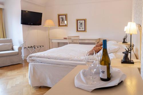 a room with a bed and a bottle of wine on a table at Möckelsnäs Herrgård in Diö