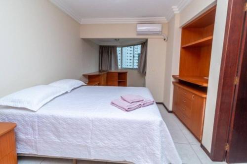 1 dormitorio con cama blanca y vestidor en Ap Balneário Camboriú - Próximo Roda Gigante, en Balneário Camboriú