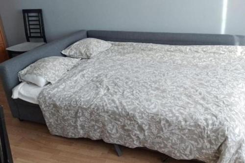 a bed with a gray comforter and two pillows at 50m2 Apartment FREE Parking + Laundry 20min Center in Espoo