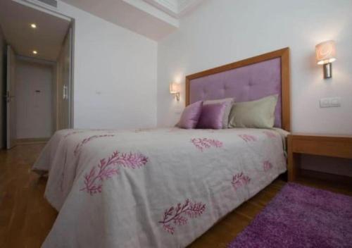 a bedroom with a large bed with a purple bedspread at Superbe appartement à la corniche de Casablanca in Casablanca