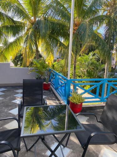 a patio with two tables and chairs and palm trees at Blue paradise Villa in Triolet
