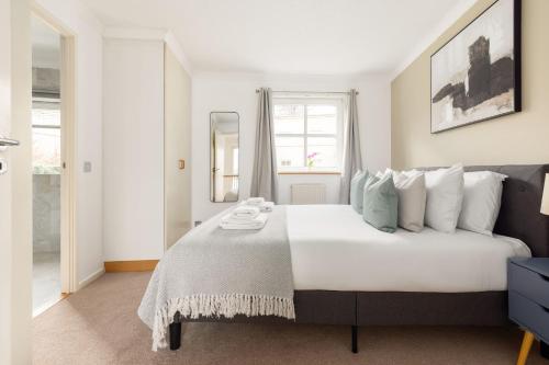 een slaapkamer met een groot wit bed en een raam bij The Canada Water Apartments in Londen