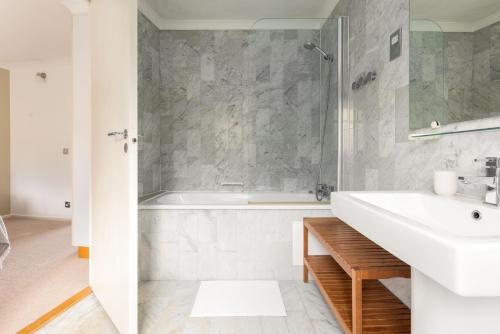 a white bathroom with a tub and a sink at The Canada Water Apartments in London