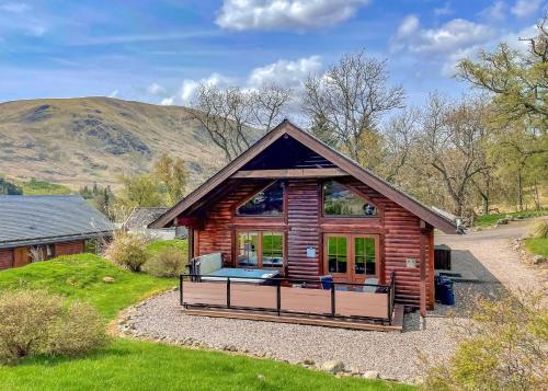 Glen Clova Lodges في Inchmill: كابينة خشبية مع شرفة كبيرة على ممر الحصى