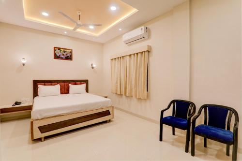 een slaapkamer met een bed en twee blauwe stoelen bij OYO Hotel Ambika Palace in Patna