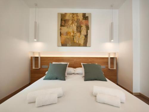 una camera da letto con un grande letto bianco con due cuscini di Galleria Roma Art Guesthouse a Oristano
