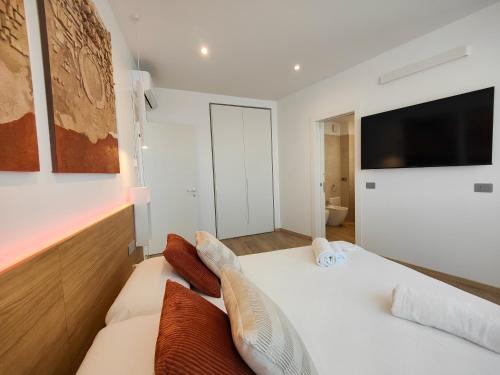1 dormitorio con 1 cama y TV en la pared en Galleria Roma Art Guesthouse, en Oristano