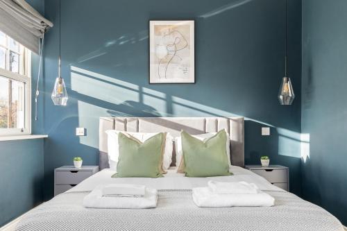 a bedroom with blue walls and a bed with two pillows at The Putney Villas in London