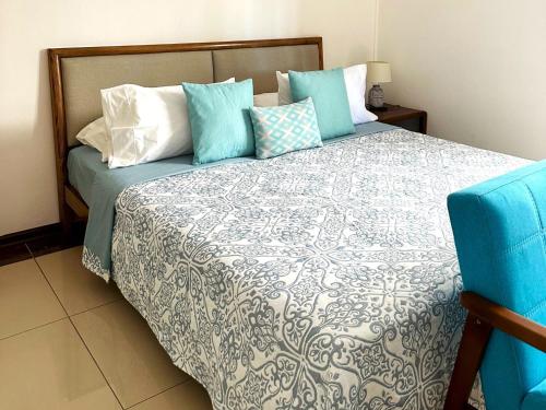 1 dormitorio con 1 cama con almohadas azules y blancas en Residence Le Point Choisy en Pointe aux Cannoniers