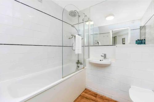 a white bathroom with a sink and a mirror at 1 Bed Garden Flat in Belsize Park next to station! in London