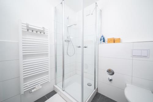 a white bathroom with a shower and a toilet at Deluxe Apartments - 1 & 2 Bedroom - Zentral - 10 Min Messe in Düsseldorf