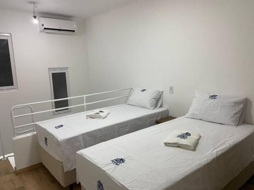 Duas camas num quarto com paredes brancas em Loft no Espinheiros - Joinville/SC em Joinville