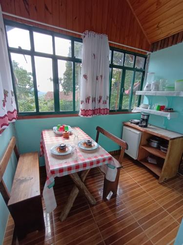 una pequeña cocina con mesa, mesa y sillas en Casa Dell Angelo Apartamentos, en Visconde De Maua