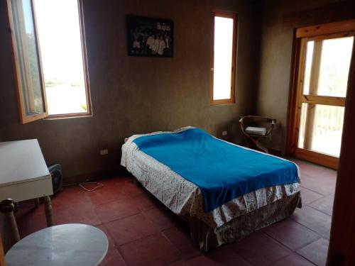 a bedroom with a bed and a table and windows at Alquiler Casa Campo Ica in Ronceros Bajo