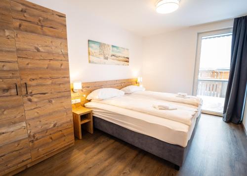 a bedroom with a bed and a wooden wall at Haus Tauernblick Katschberg by AlpenTravel in Katschberghöhe