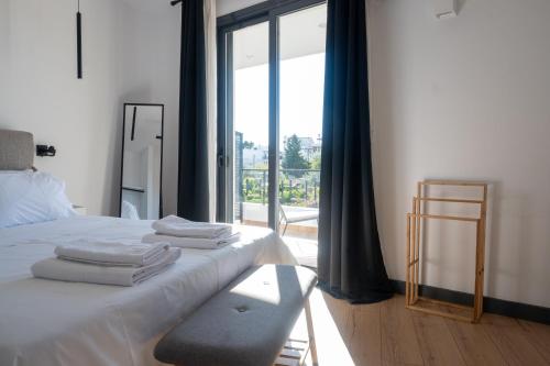 1 dormitorio con 1 cama con sábanas blancas y ventana en Χαλάρωση με στυλ στο κέντρο Αγίων Θεοδώρων en Agioi Theodoroi