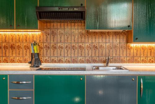 a kitchen with green cabinets and a sink at Hotel Diffuso Locanda Elisa in Dimaro