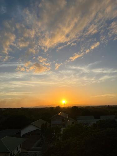 um pôr-do-sol sobre uma cidade com o sol no céu em PECHO PERFECT SUITE WITH MASSAGE CHAIR em Cavite