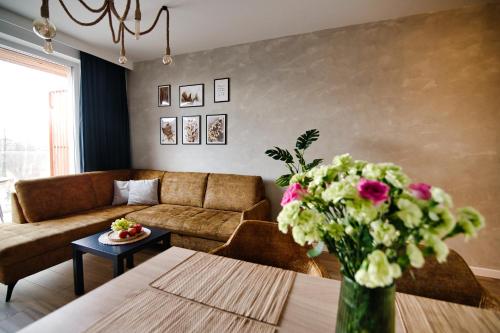 - un salon avec un canapé et une table fleurie dans l'établissement Apartamenty Laguna Beskidów - A67, à Zarzecze