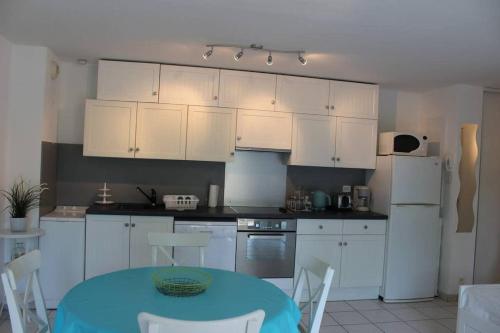 uma cozinha com armários brancos e uma mesa e cadeiras azuis em appartement cosy et nature au coeur du Bassin em Arès
