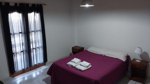 een slaapkamer met een paars bed met 2 handdoeken erop bij Departamentos Pequeña Ramona in San Rafael
