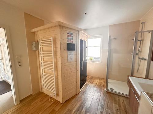 a bathroom with a walk in shower and a wooden cabinet at Haus Hobbingshof Greetsiel in Greetsiel